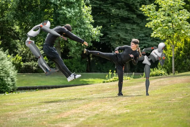 Two free runners doing kicking moves in a park with mocap Xsens Link suits