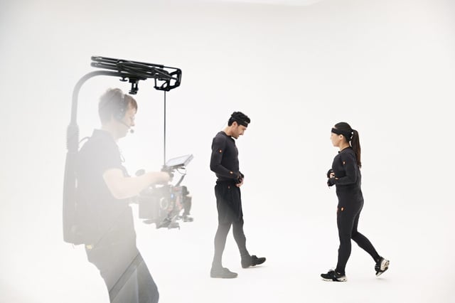 Camera man holding a camera filming two mocap models in Xsens Link suit